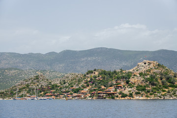 Fototapeta premium Kalekoy village with stone built houses and castle on top of hill in Uchagiz bay in Turkey