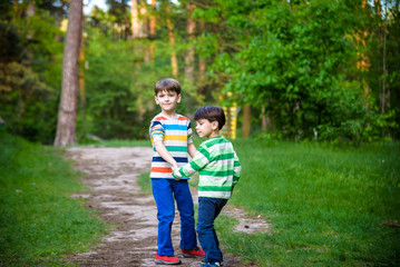 Fototapeta premium childhood, hiking, family, friendship and people concept - two happy kids walking along forest path