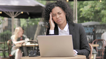 African Businesswoman with Headache Using Laptop in Outdoor Cafe