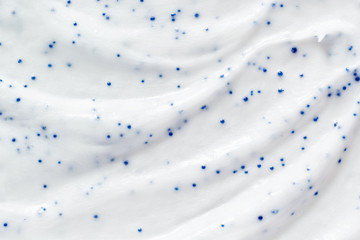 White cream scrub cleanser background. Skin care face scrub with blue particles texture. Cosmetic...