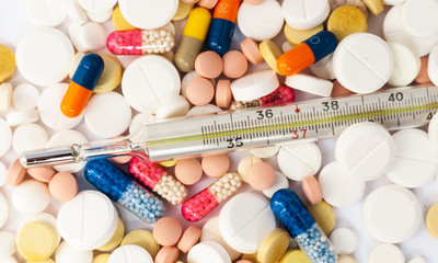 Thermometer and pills, medicine for pneumonia, antibiotics on an pink background. Coronavirus,...