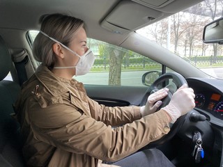 young woman driving a car. girl in a protective mask and gloves, against coronavirus, driving a car. Covid-19.