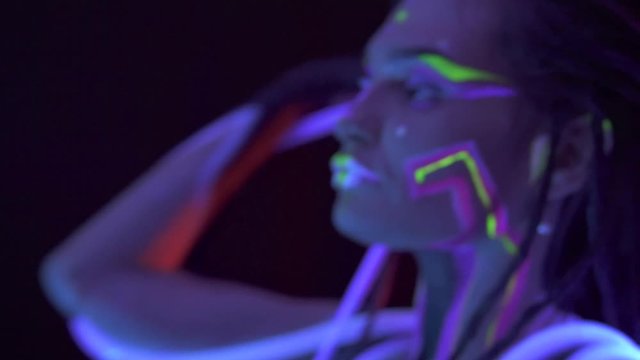 Portrait of a Girl with Dreadlocks in Neon UF Light. Model Girl dancing with glowing tubes with Psychedelic MakeUp, Art Design of Female Disco Dancer Model in UV, Colorful Abstract Make-Up.
