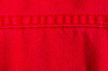 clothing items stonewashed red cotton fabric texture with seams, clasps, buttons and rivets, macro