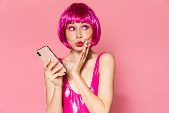 Image of party girl wearing wig making kiss lips and using mobile phone