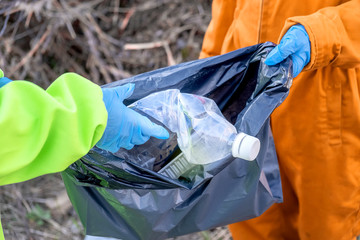 Two volunteers stack plastic trash in a black bag