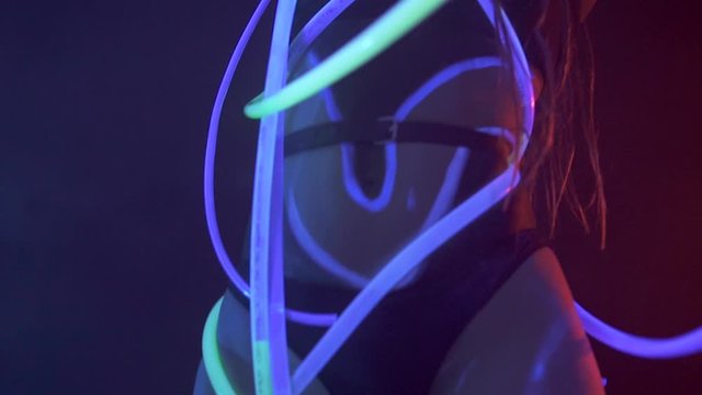 Portrait of a Girl with Dreadlocks in Neon UF Light. Model Girl dancing with glowing tubes with Psychedelic MakeUp, Art Design of Female Disco Dancer Model in UV, Colorful Abstract Make-Up.