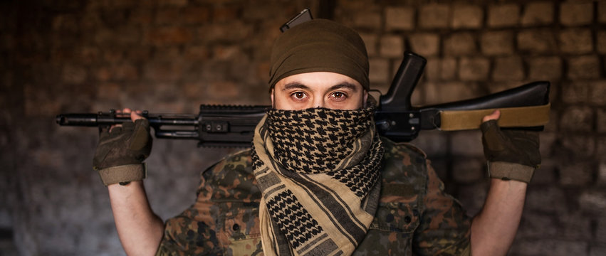 Arab male soldier in a headdress from the national keffiyeh with weapons in his hands. Muslim with firearms
