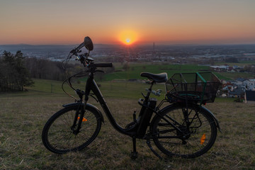 Fototapeta na wymiar Black electric bike on ski slope in Budweis city with sunset