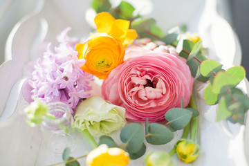 Beautiful colorful flowers in a glass bottles on a vintage wooden tray.