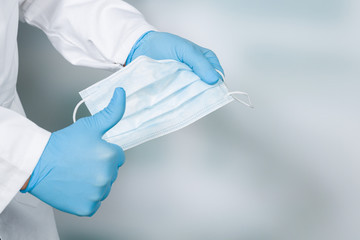 close up of doctor's hand with a medical face mask for virus protection showing thumbs up