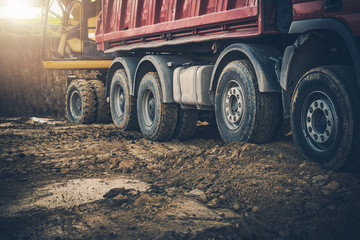 Fototapeta Construction Site With Worker Moving Soil From Backhoe To Dump Truck. obraz