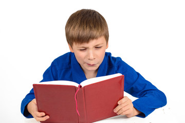 boy schoolboy in a blue t-shirt is preparing for school, carefully reading something in the book