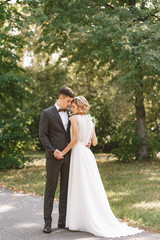 Bride and groom. Portrait of a man in a suit and a woman of a blonde in a white dress on nature on the wedding day.