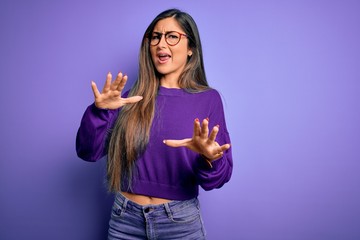 Fototapeta premium Young beautiful smart woman wearing glasses over purple isolated background afraid and terrified with fear expression stop gesture with hands, shouting in shock. Panic concept.