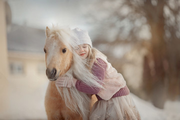 Little girl with palomino miniature horse stallion in winter park - 345685075