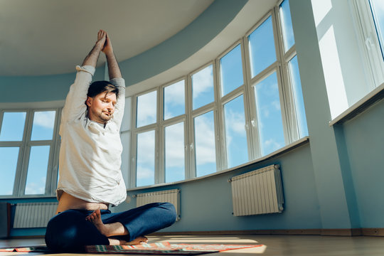 Man practice yoga. Young attractive male doing breathing exercises. Guy meditating at home along during the pandemic. Relaxation and resting concept for isolation. Slide shot.