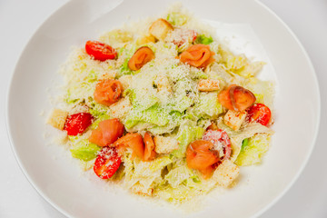Caesar salad with salted salmon fish on a white plate