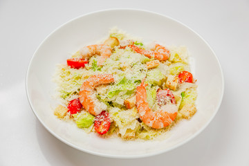 Caesar salad with prawns on a white plate