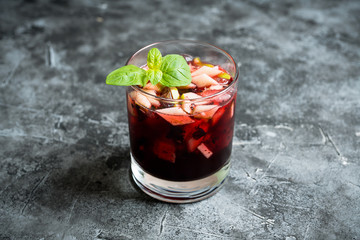 Old fashioned cocktail with blackberry liqueur and apple slices on rustic background. Selective focus. Shallow depth of field.