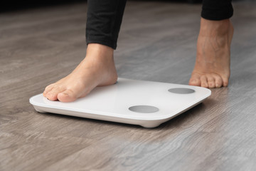 closeup female legs without shoes stand with one foot on the scales. weight measurement concept