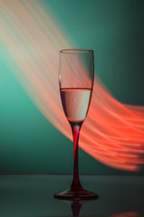 Transparent glass of champagne with red lights around