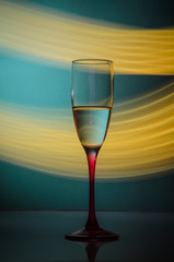 glass of champagne on green background with yellow light trails