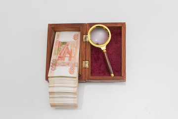 Russian banknotes of five thousand rubles in large quantities in a wooden box with a magnifying...
