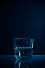 Glass with cold blue light on dark background