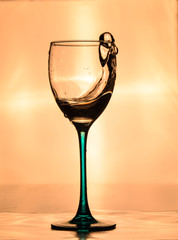 Transparent glass with water on orange background