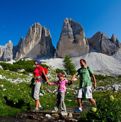 Fototapeta na wymiar Happy family outdoor adventure with kid in Dolomites mountain in summer time in Italy. Concept of travel, friendly family.