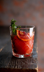 Old-fashioned cocktail with blood oranges and thyme on the rustic background. Selective focus. Shallow depth of field.

