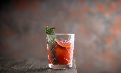 Old-fashioned cocktail with blood oranges and thyme on the rustic background. Selective focus....
