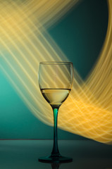 glass of wine with yellow neon trails on the table
