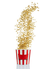Flying popcorn from red and white paper striped bucket isolated over the white background. Cinema style popcorn