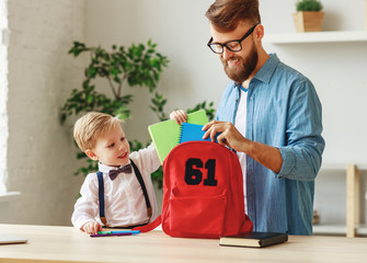 Father and kid preparing school backpack.