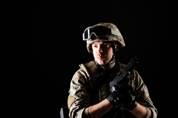 Fototapeta premium Soldier with gun is on mission on black background. Concept of war.