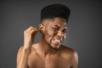 Beauty portrait of man using cotton swab standing isolated over gray background