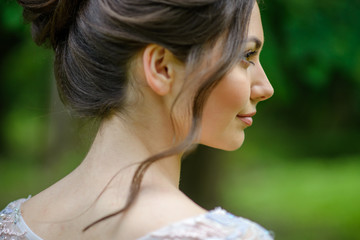 Close-up portrait of a young girl. The girl is standing sideways. A woman's curl falls.