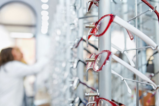 Optical Shop. Salesman And Costumer In Background. Focus On Eyeglasses 