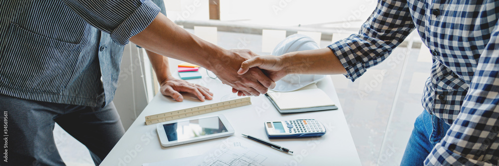 Poster architect and engineer construction workers shaking hands while working for teamwork and cooperation