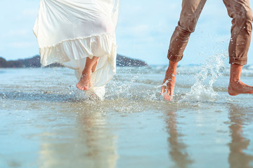 foot of romantic couple running and water splash on beach. Man and woman in love. People travel concept.
