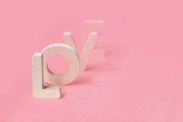 Love from wooden letters on pink background. Love goes. Dissolves, outgoing love concept