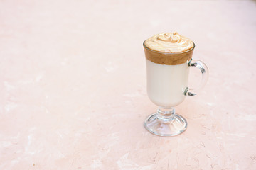 A popular Korean drink during self-isolation is Dalgona coffee. A delicious modern cold beverage in glass stands on a light beige concrete background with a copy space.