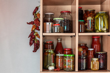 Homemade vegetables in jars on wooden shelves in the home pantry. Pickled food, as stocks from the autumn harvest, will be useful for self-isolation. Healthy healthy food from the garden.