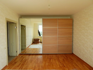 Flat pack furniture wardrobe with a mirror installed wall to wall in a small apartment room