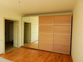 Flat pack furniture wardrobe with a mirror installed wall to wall in a small apartment room