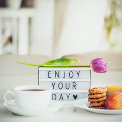 Good morning concept. Romantic breakfast - cup of hot drink, cookies, lightbox with message Enjoy...