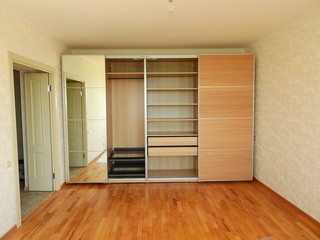 Flat pack furniture wardrobe with a mirror installed wall to wall in a small apartment room