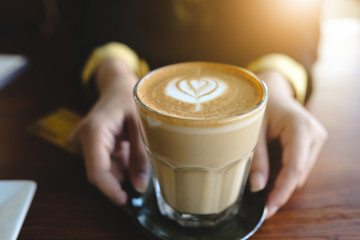 Young woman holding coffee cup with heart symbol